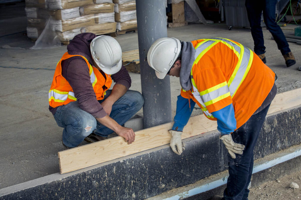 Two construction workers checking the alignment of a building element at a construction site