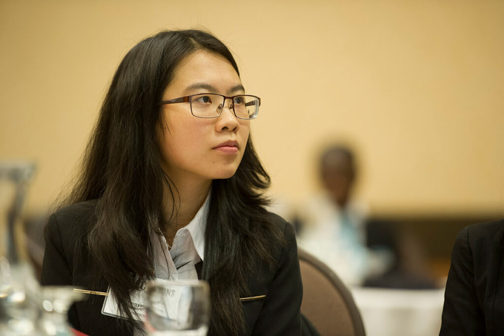Woman dressed in business attire sitting at a table at a conference