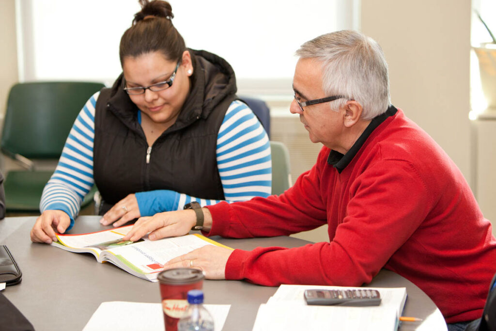 Instructor and student reading a textbook