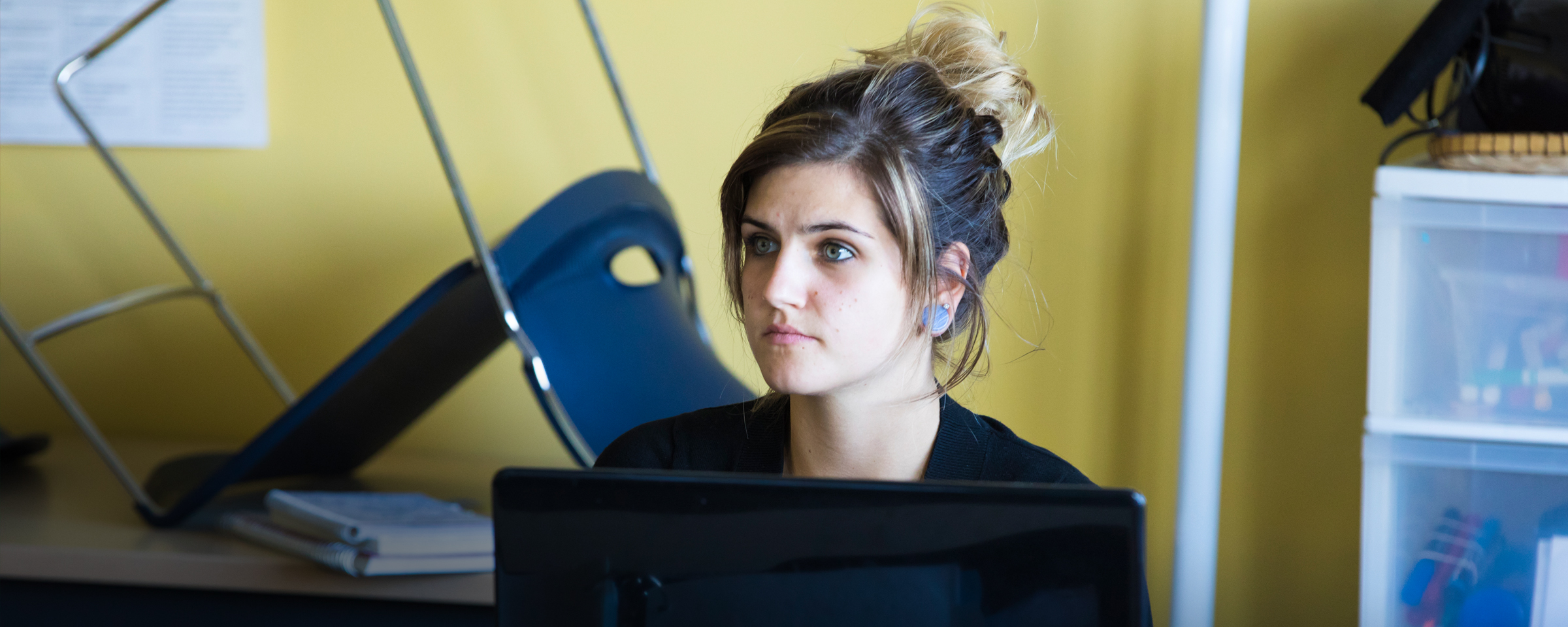 Girl sitting behind computer monitor in classroom