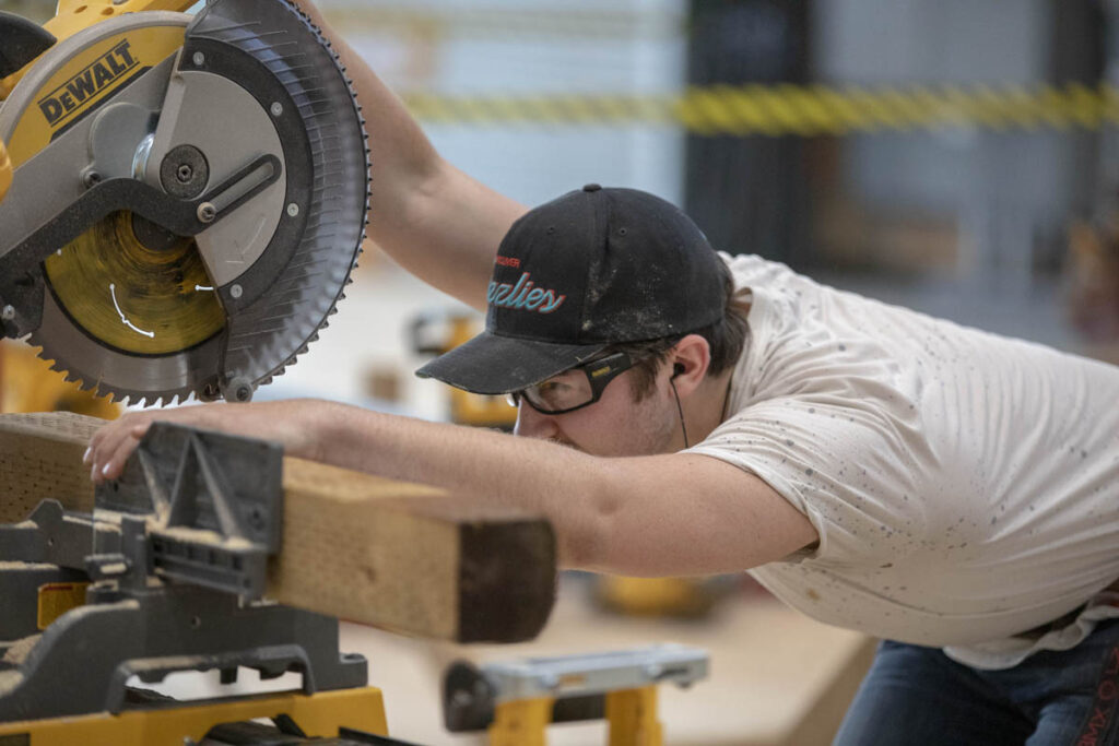 Carpentry student sawing wood in a carpentry shop