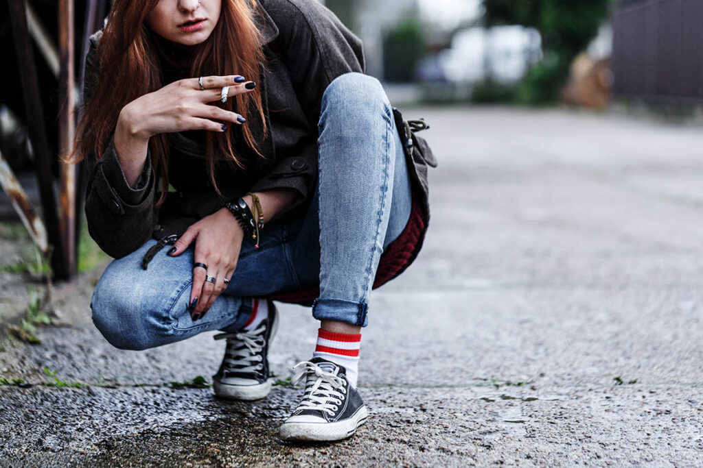 Girl crouched down and holding a cigarette in her hand