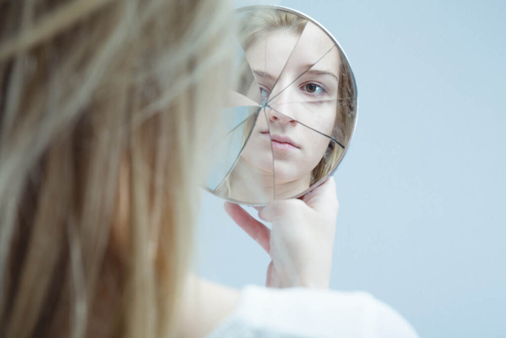 Girl looking at herself in a broken mirror