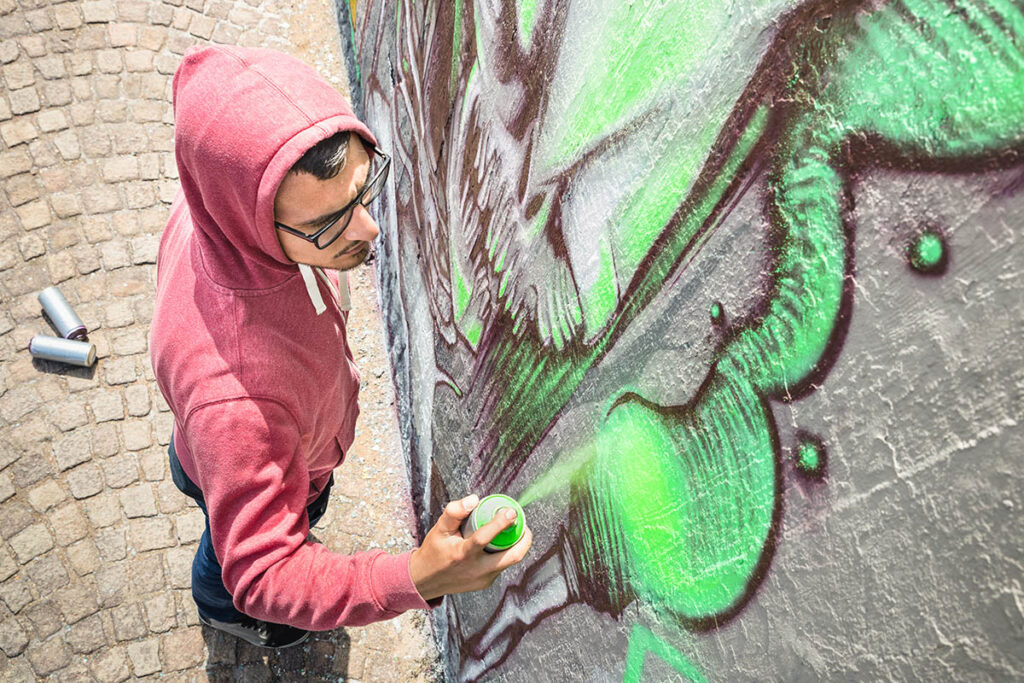 Graffiti artist spray painting a building