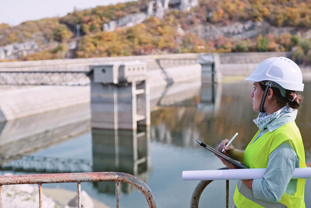 Engineer making notes while looking at a dam