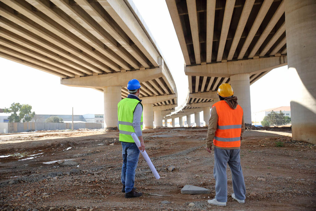 Two engineers looking up at a bridge under construction