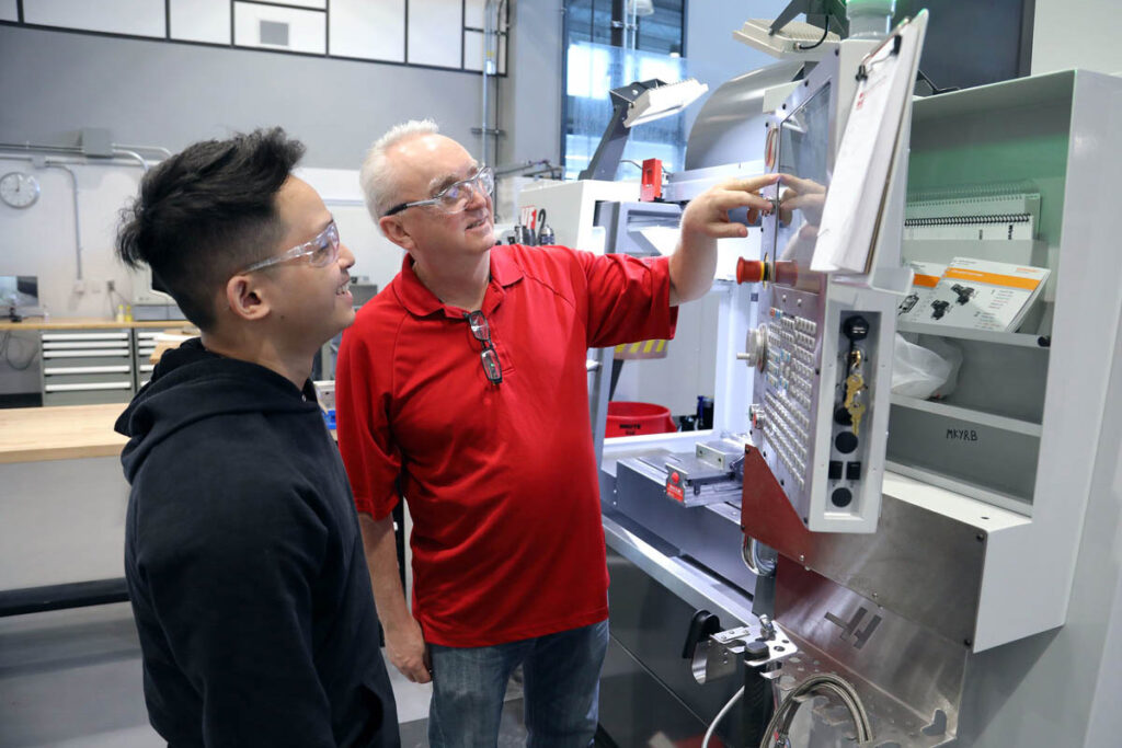 Instructor showing student how to operate a CNC machine