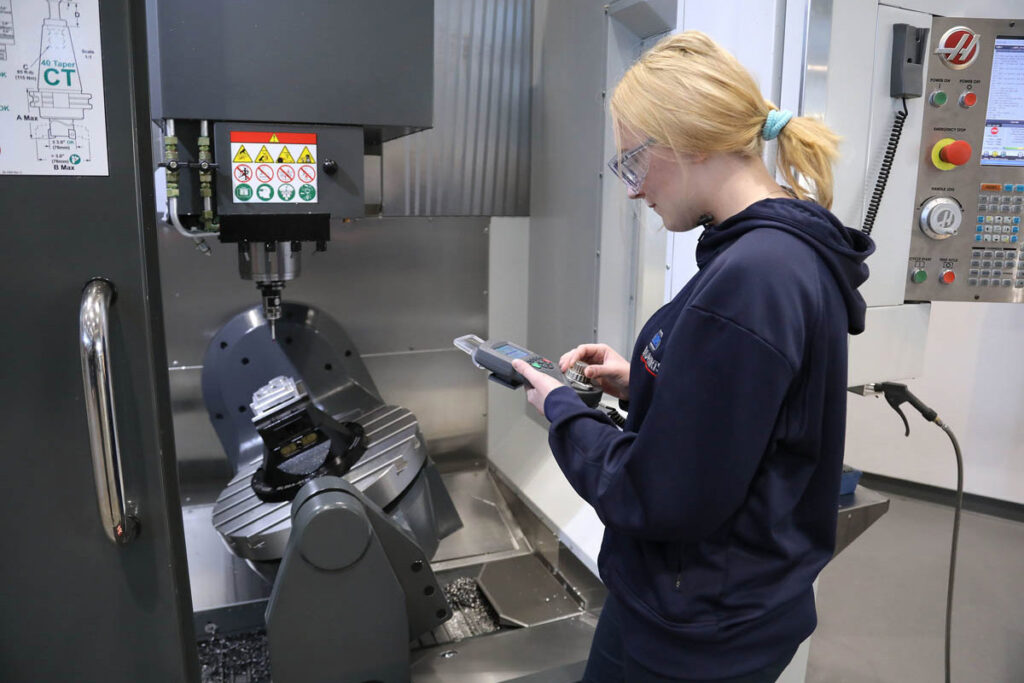 Student holding a remote control for large machine in front of her