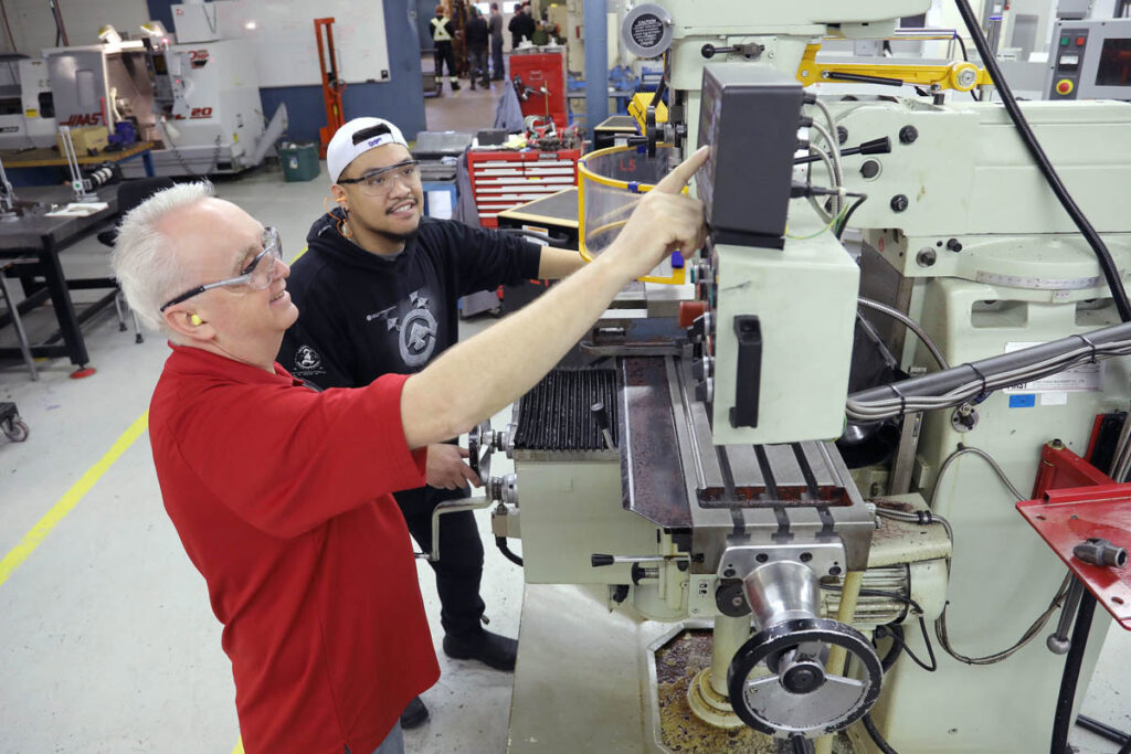 Instructor showing student how to work CNC machine