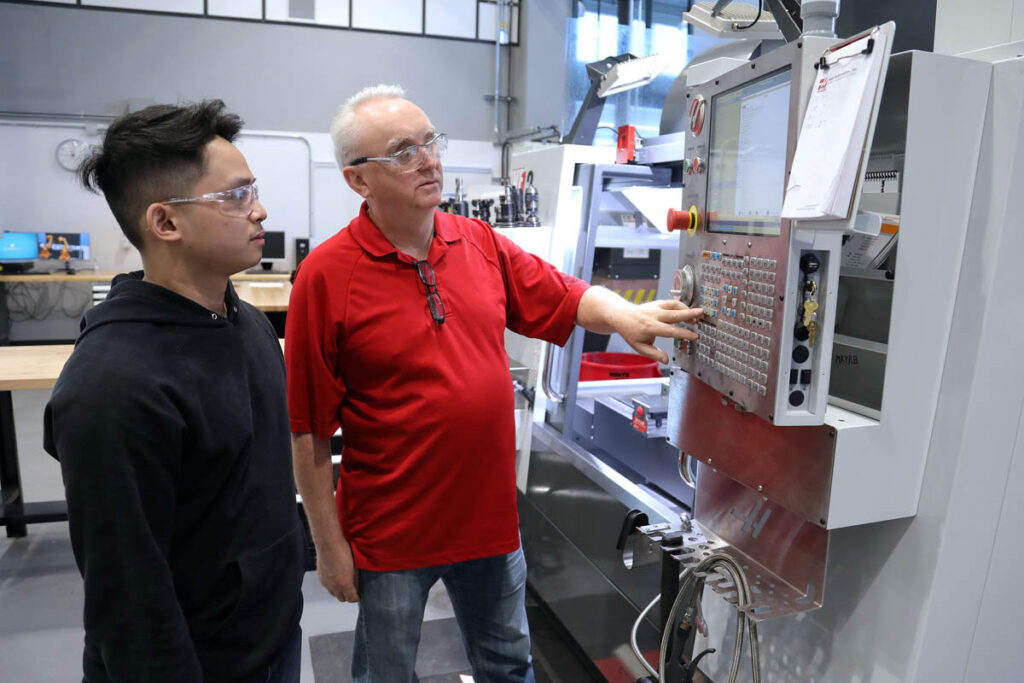 Instructor showing student how to operate CNC machine