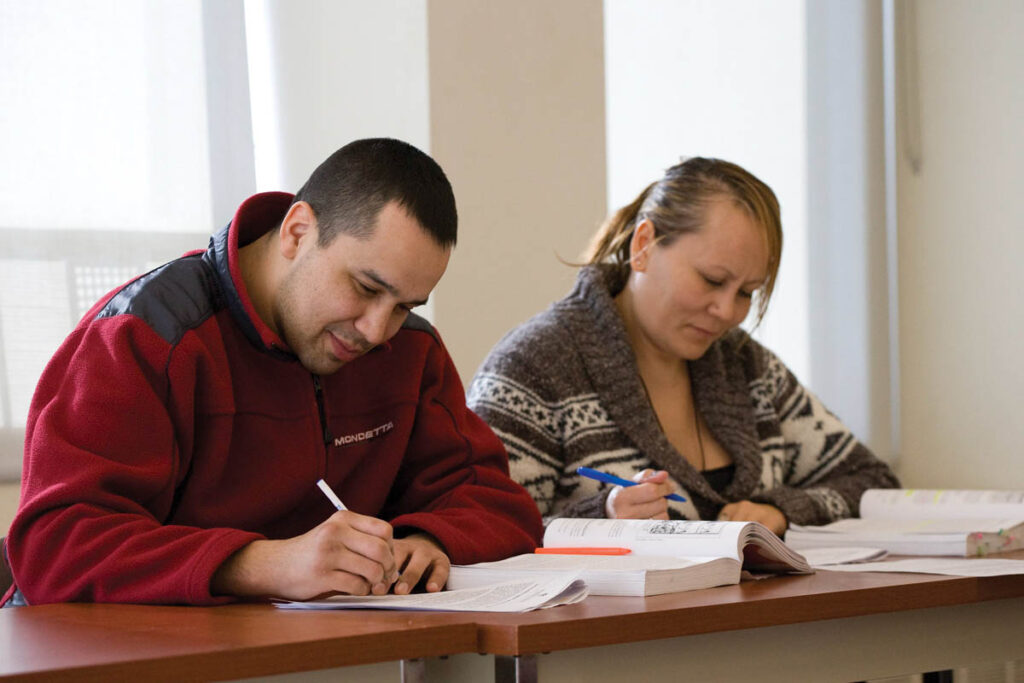 Two students taking notes in a classroom