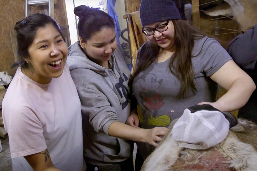 Three students participating in a buffalo tanning activity