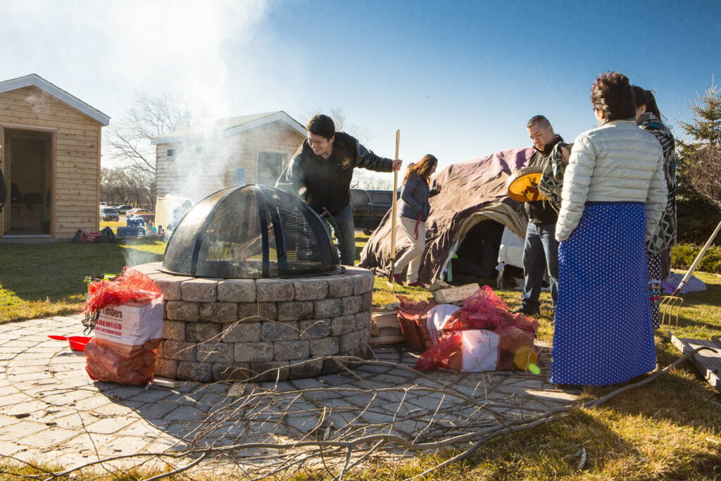 Group of people outdoors near a fire pit by the sweat lodge