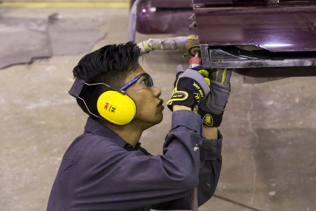 Collision repair student working on a vehicle in a shop