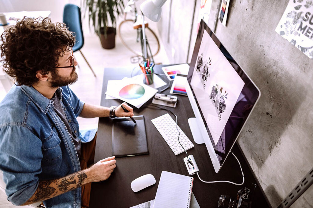 Designer working on a computer with a colour wheel on the desk