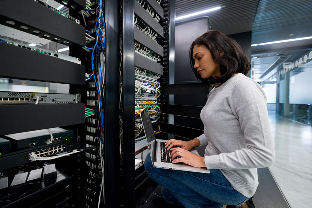 Woman typing on a laptop in a networking lab