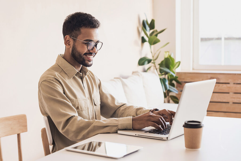 Man sitting at a dining room table using his laptop