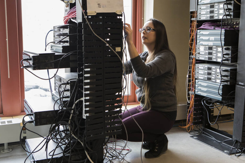 Woman connecting wires in a networking lab