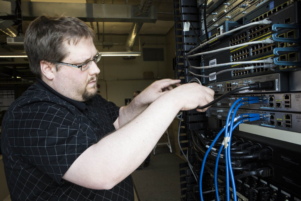 Man plugging in wires in a networking lab
