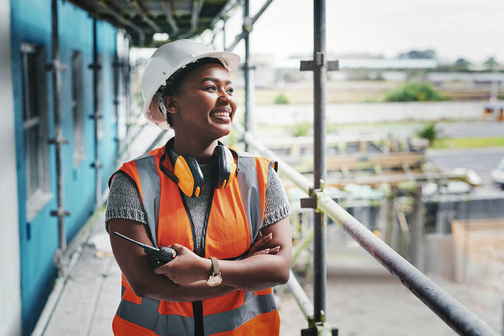 Smiling woman in hard hat and safety vest at a construction site