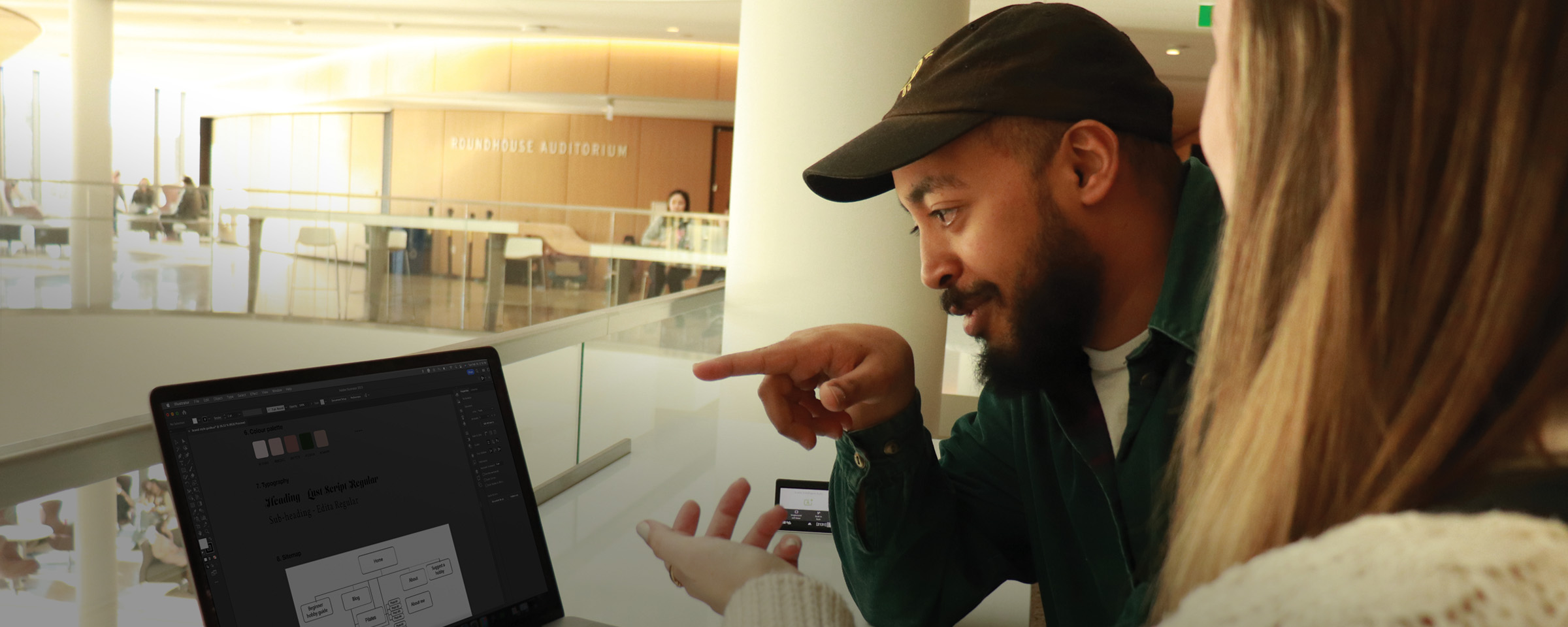 Student pointing at laptop screen in an atrium