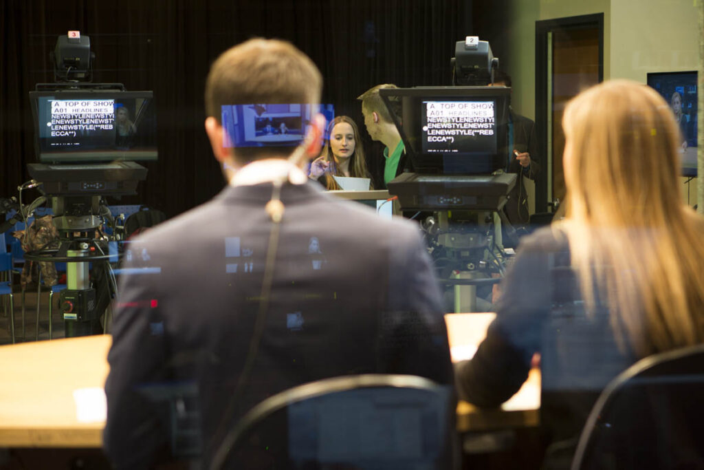 Two people sitting at a news desk in a TV studio