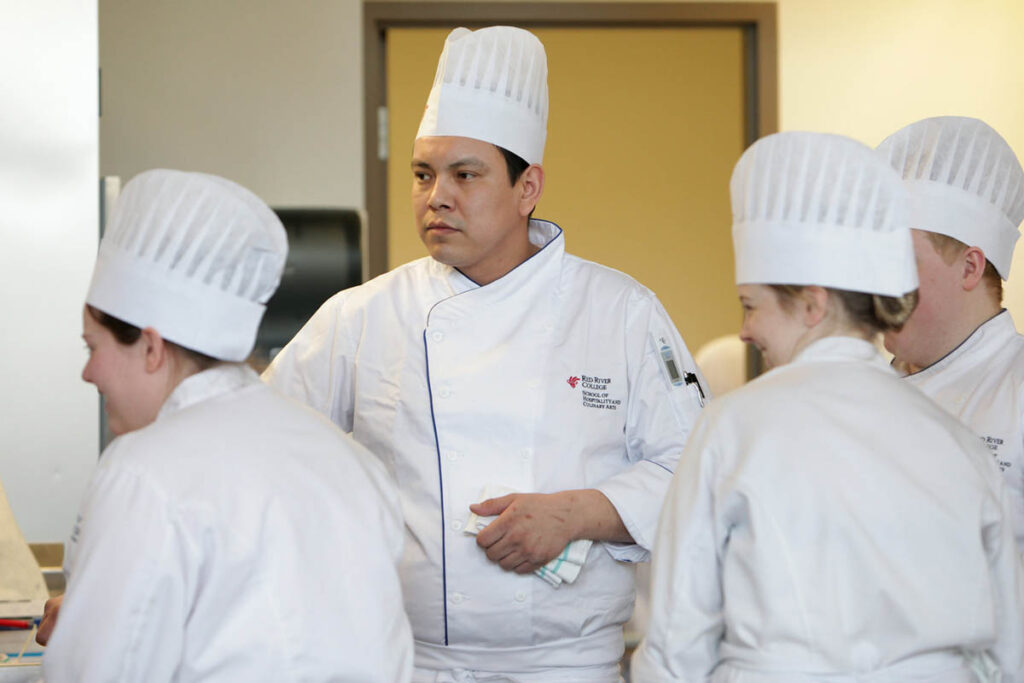 Culinary instructor talking to students in a kitchen