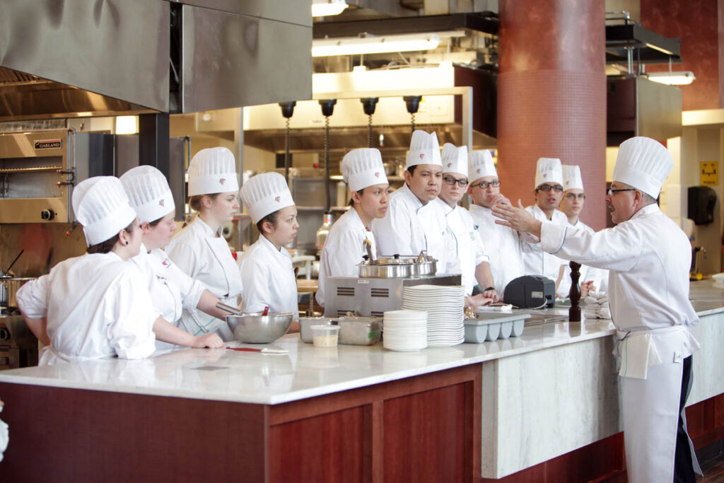 Class of culinary students listening to instructor talk in a restaurant