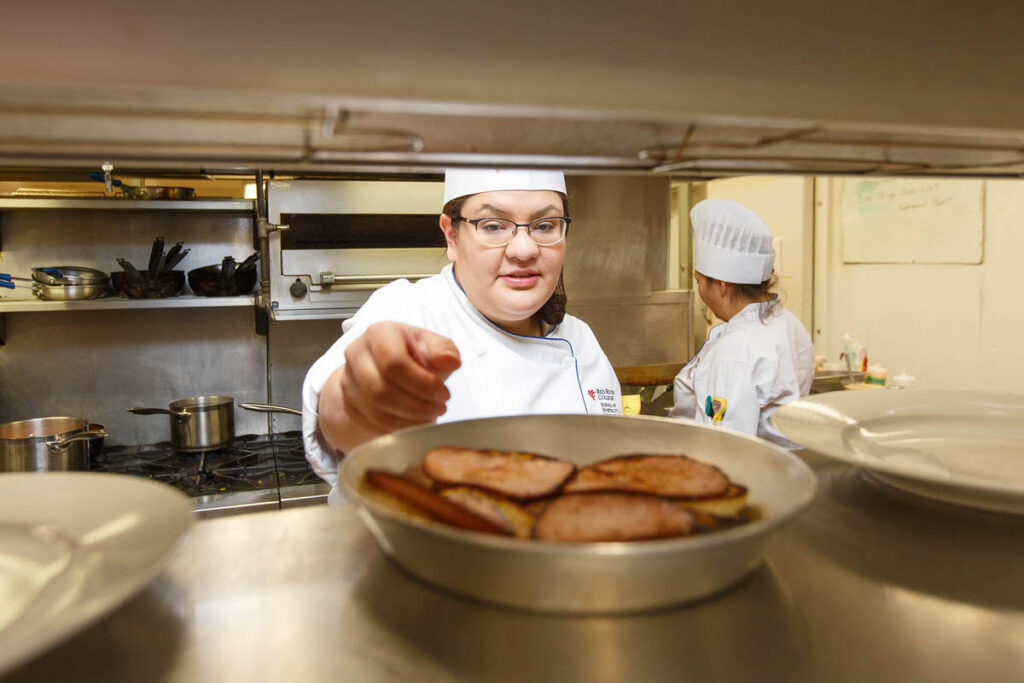 Culinary student reaching for food on shelf in a kitchen