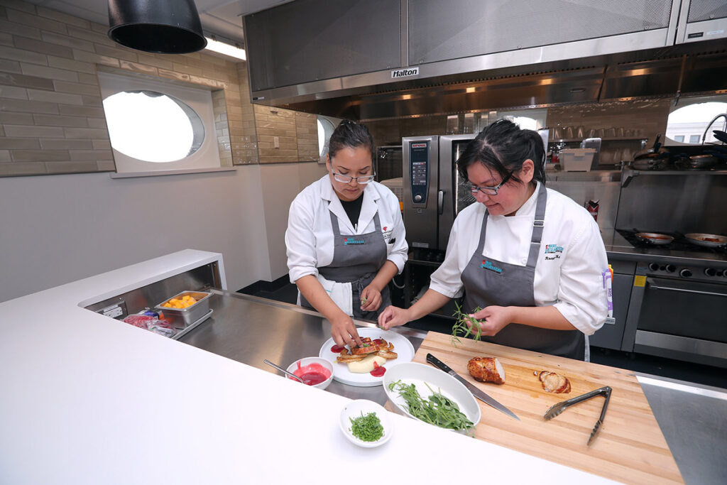 Two culinary students preparing a dish in a kitchen