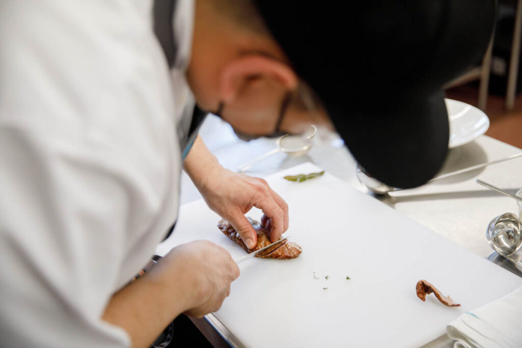 Culinary student cutting meat in a kitchen