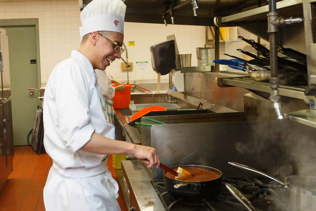 Culinary student stirring sauce in a pot