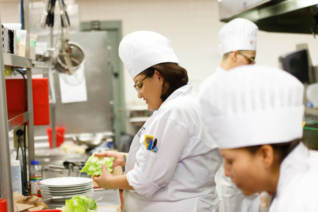 Culinary student working with lettuce in a kitchen