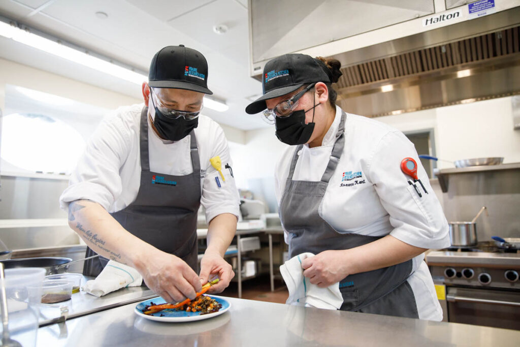 Two culinary students preparing a dish in a kitchen