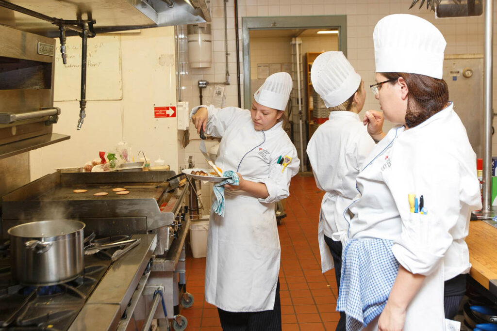 Culinary instructor showing students how to prepare a dish