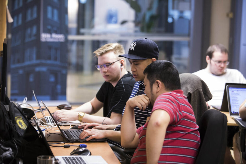 Group of students sitting around a laptop in a classroom