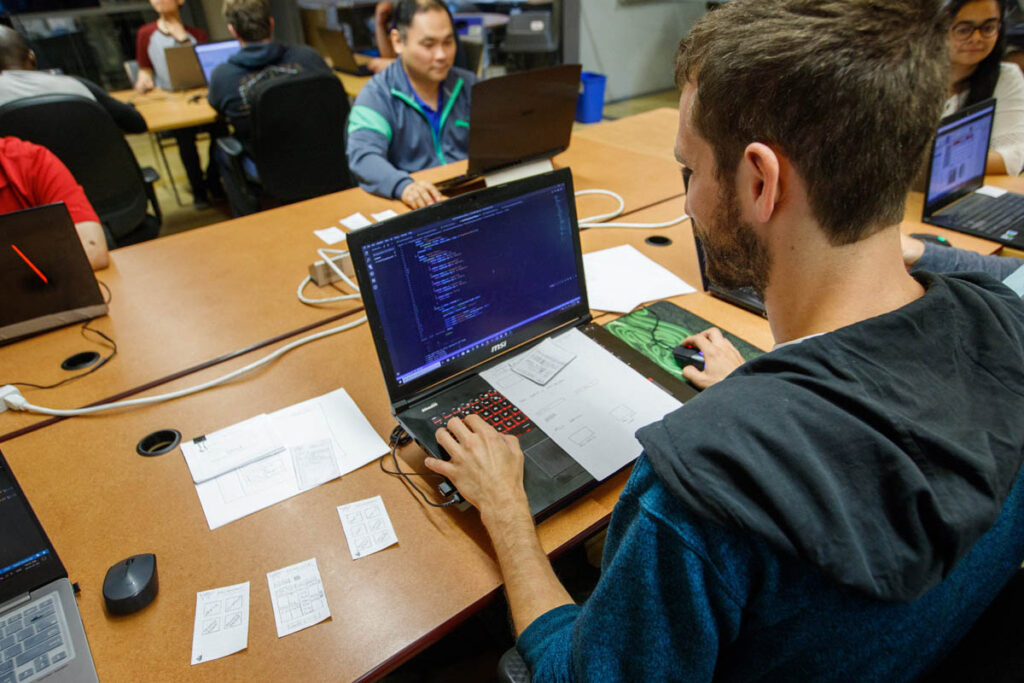 Guy working on a laptop in a classroom