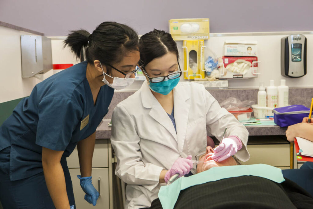 Dental assisting student practicing in a dental lab while instructor watches