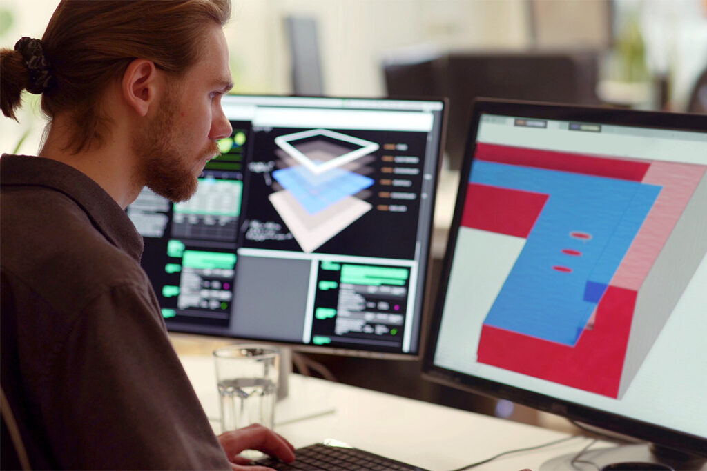 Man sitting at a computer with drafting software open on two monitors