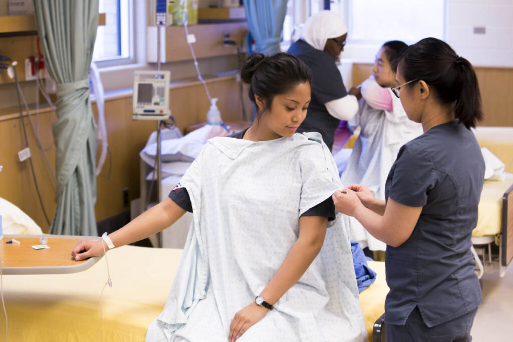 Nursing student helping patient put gown on
