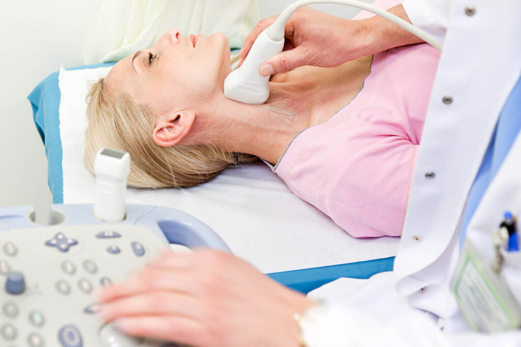 Medical professional taking ultrasound of woman's neck and throat