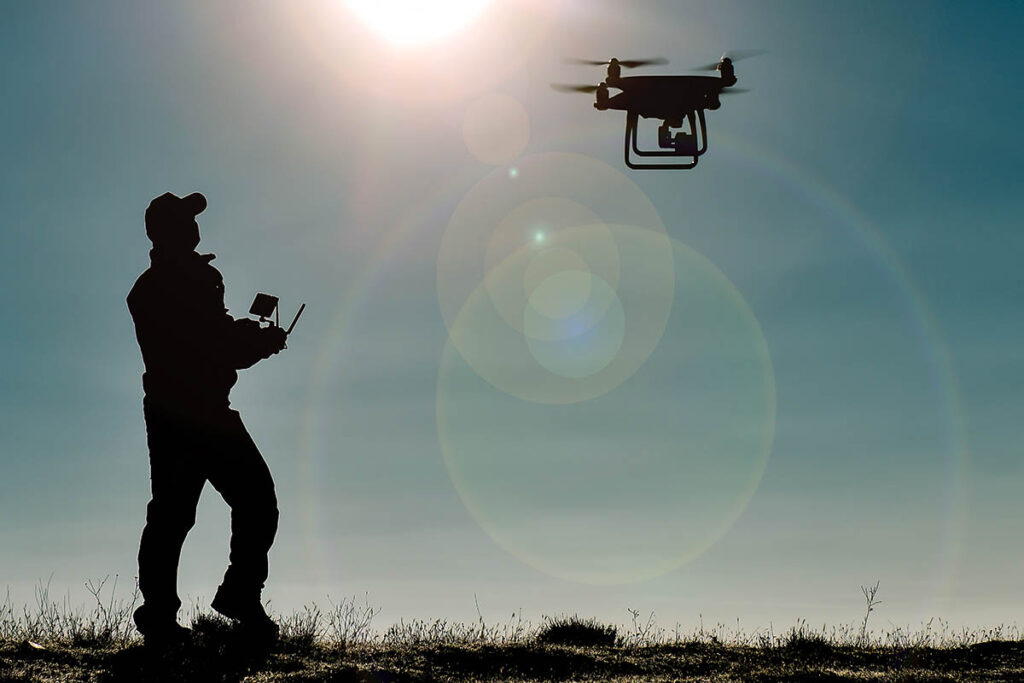 Silhouette of person operating a drone on a sunny day outside