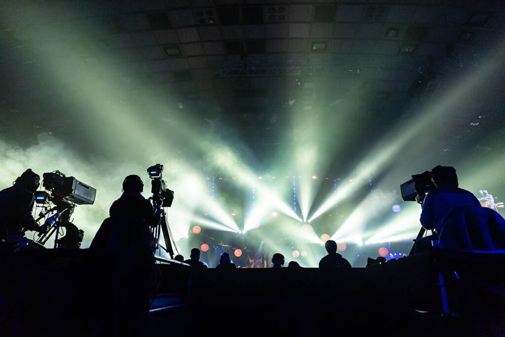 Silhouette of camera operators at a concert with bright lights