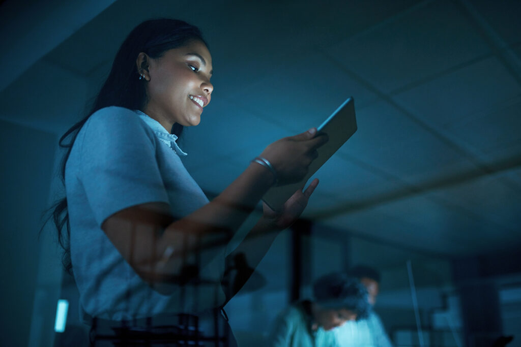 Woman standing and looking at a tablet in a dark room