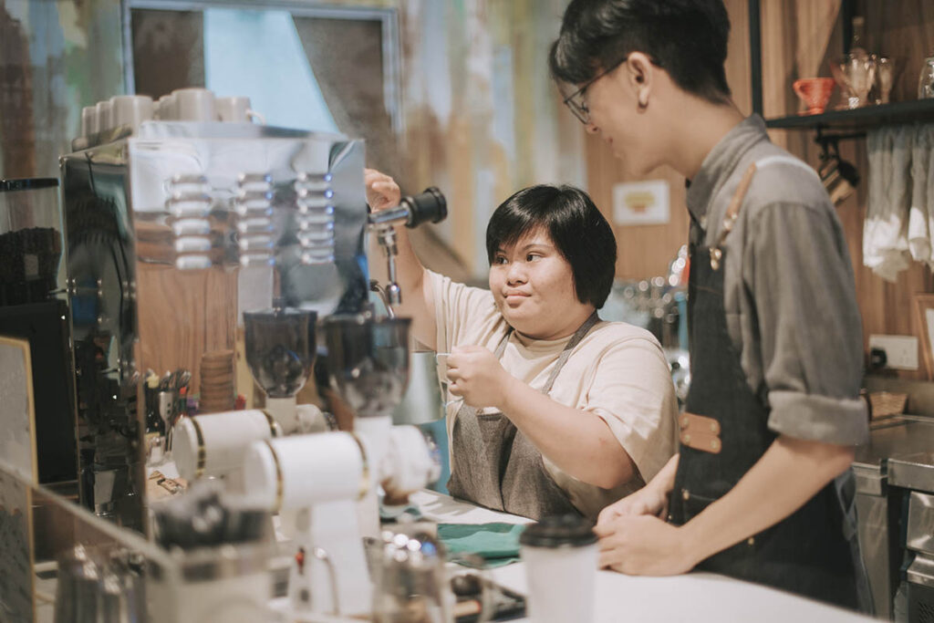 Support worker and client pouring coffee in a coffee shop
