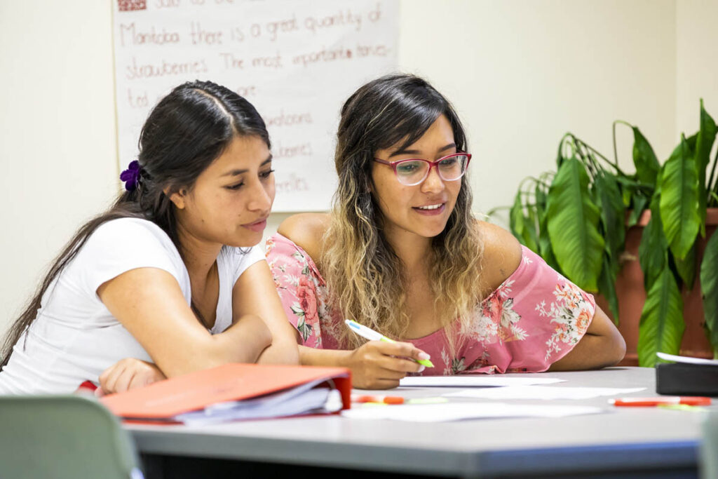 Two students taking notes in a classroom