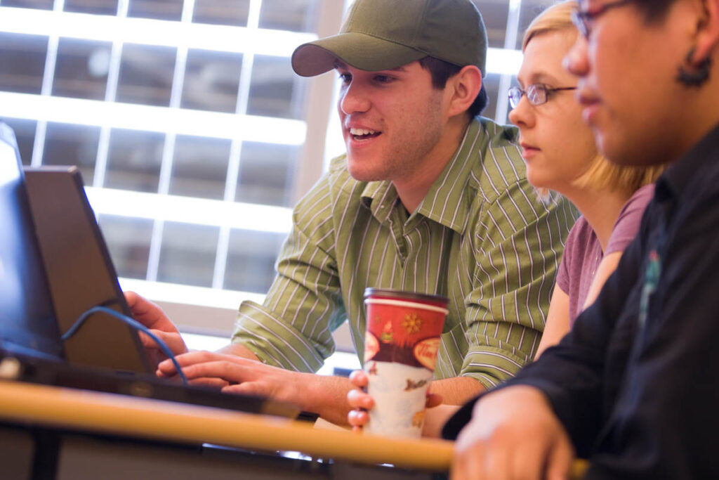 Three students sitting around a laptop