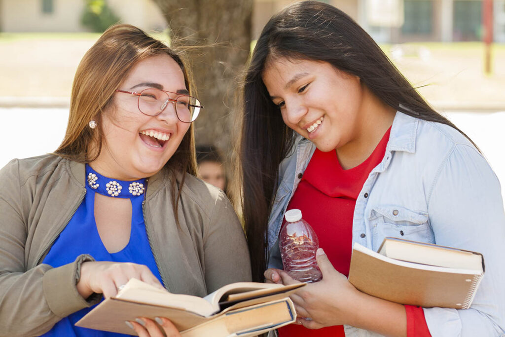 Two students laughing as they read a book