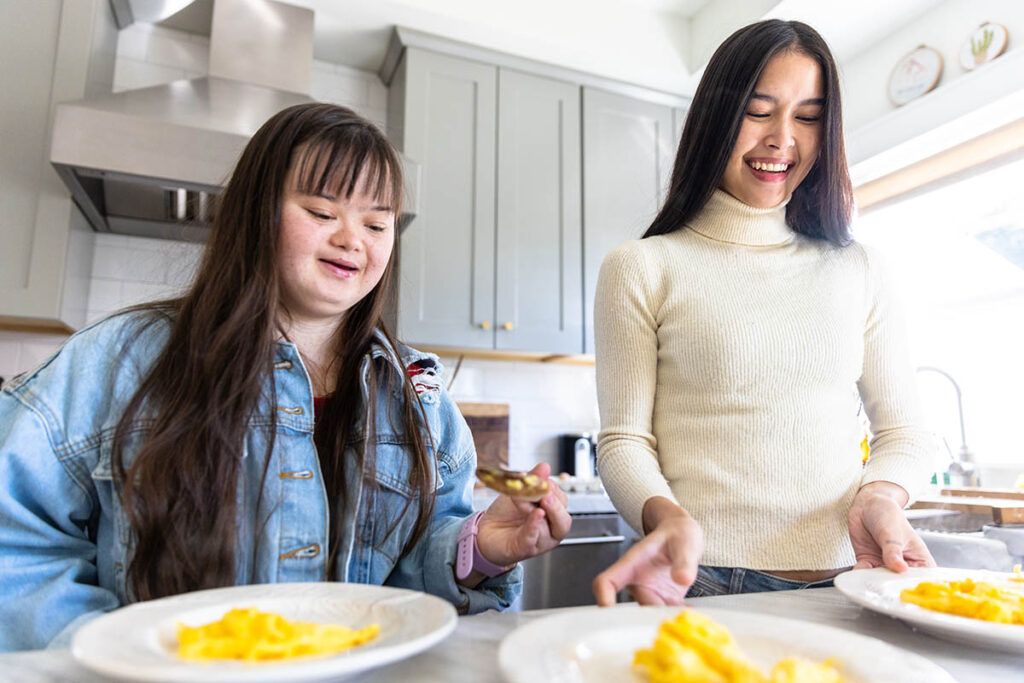 Support worker and client eating in kitchen