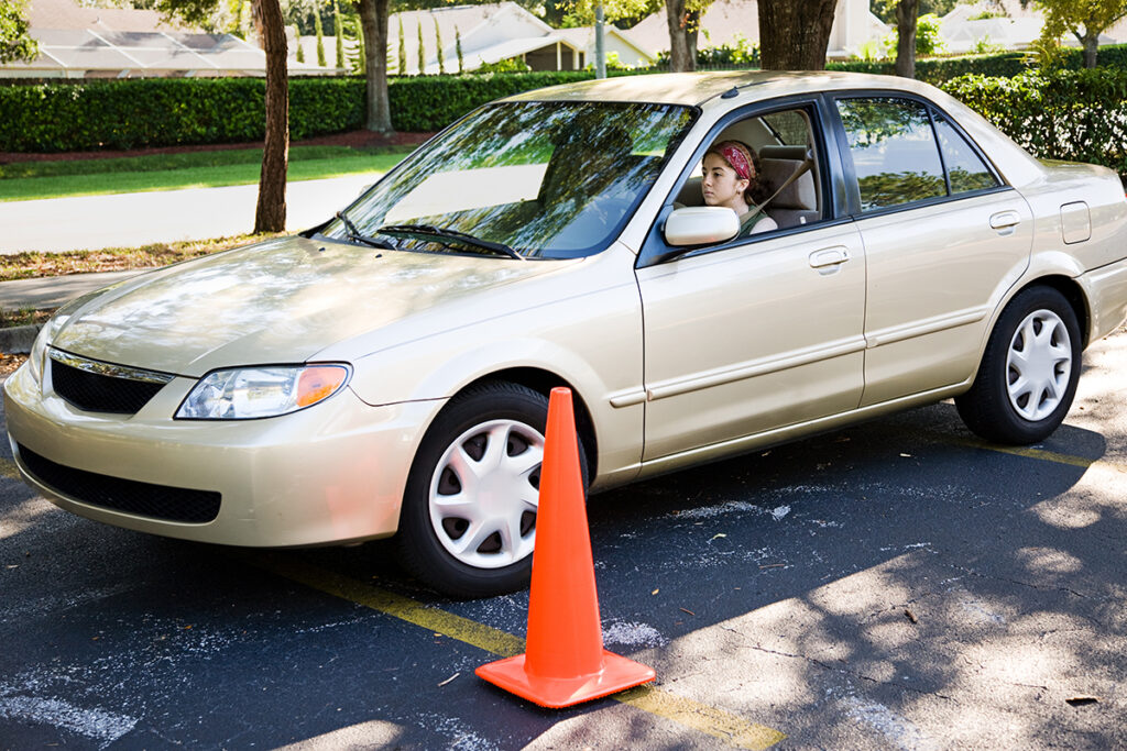 Car driving past orange pylon on parking lot